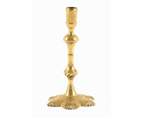 A Queen Anne brass candlestick, with shell cast base.  Height 25 cm.