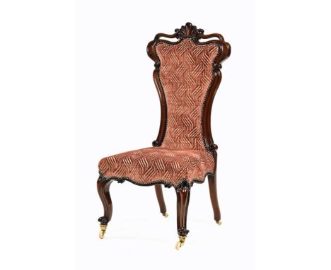 A Victorian mahogany nursing chair, with shaped back, stuffover seat and raised on cabriole front legs terminating in brass a