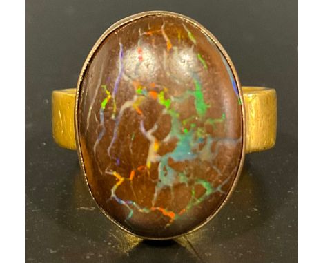 A tested 9ct rose gold mounted cabochon boulder opal on a 22ct gold ring, the oval cabochon boulder opal measuring approx. 17