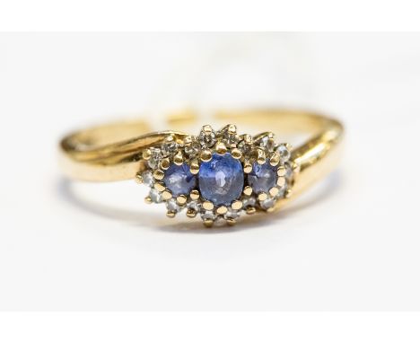 A sapphire and diamond set ring, the three pale blue sapphires set to the top, with a border of claw set diamonds, 9ct gold, 