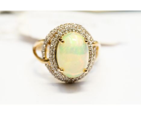 An opal dress ring, oval opal approx 9mm x 13mm, with a double open border of pave set white zircons, 9ct gold, size Q, total