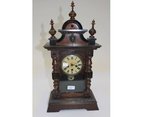 A German mantle clock, the frame with turned pilastis and domed pediment and with cream enamel dial and Roman numerals A/F