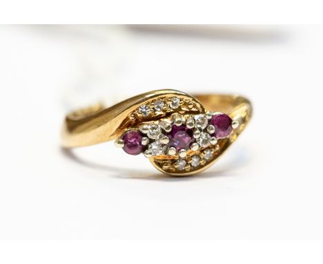 A ruby and diamond dress ring, the front set with three round rubies with alternate diamond accents and diamond set cross ove