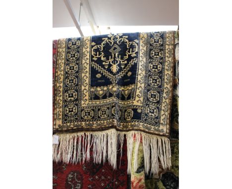 Wool runner with navy blue ground and gold patterned decoration with long fringe (one side frayed) 128 cms x 78 cms