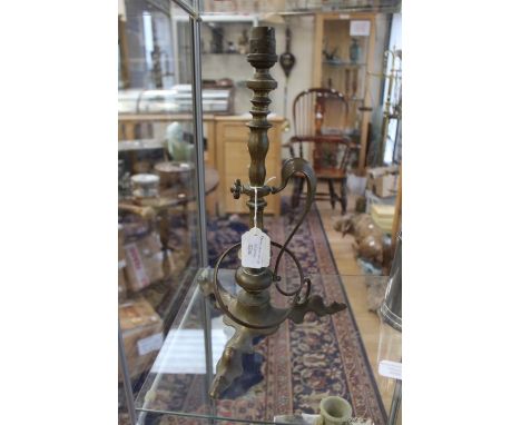 An Arts and Crafts brass table lamp in the manner of W A S Benson, having stylised scroll handle and raised on shaped and fla