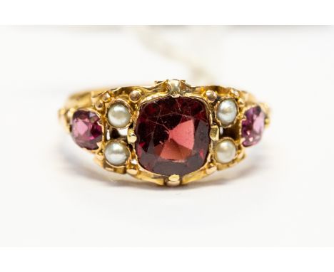 A Georgian stone set ring, cushion shaped garnet set to the centre, with seed pearl accents and pink tourmaline set to the sh