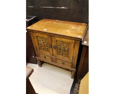 A 20th Century carved oak cabinet with one interior shelf and two small drawers at base, with metal handles, raised on solid 