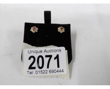 A pair of diamond and ruby ear studs in gold.