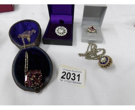 A yellow metal pendant with amethyst coloured stones, another pendant, a brooch and one other item.