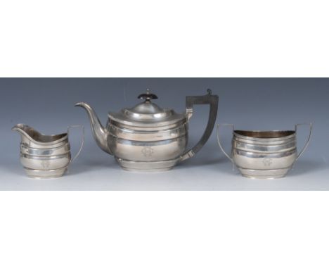 A composed George V silver three piece boat shaped tea service, comprising teapot, milk jug and sugar basin, oval knop finial