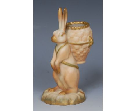 A Royal Worcester spill vase,  modelled as a hare with basket on his back, in blush ivory, picked out in green and gilt,  12c