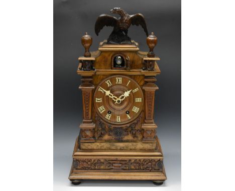 A 19th century German  Black Forest cuckoo clock, with bone Roman numerals and hands, the case with eagle finial, turned fini