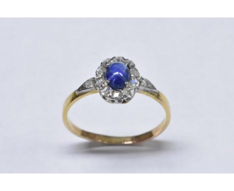 A sapphire and diamond ring, central oval blue sapphire cabochon, approx 0.35ct, surrounded by a band of ten rose cut diamond