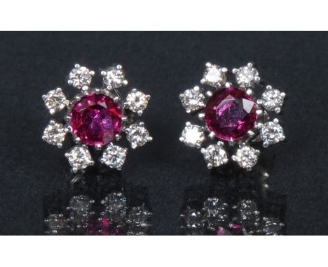 A ruby and diamond floral cluster earrings, each with a central round cut Thai ruby surrounded by a band of eight round brill