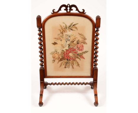 A Victorian rosewood firescreen, the arched rectangular banner decorated in Berlin woolwork, with a spray of flowers, pierced