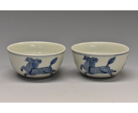 A pair of Chinese porcelain circular tea bowls, painted with longma in underglaze blue and flanked by stylized flames painted