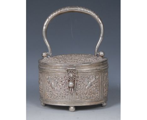 An Indian silver coloured metal oval box or caddy, hinged cover with swing handle, profusely chased with birds, flowers and d