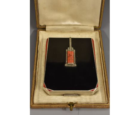 An Art Deco silver and enamel shaped rectangular lady's compact, the hinged cover centred by a coral baton carved with blosso