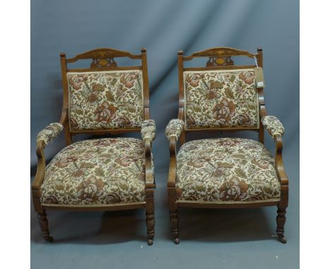 A pair of Edwardian mahogany armchairs with marquetry inlay having floral tapestry upholstery raised on turned legs and casto