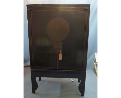 A 20th century Chinese black lacquered wedding cabinet with two doors enclosing single drawer and shelf space, raised on shap