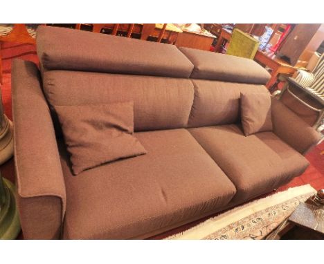 A contemporary three seater sofa with brown linen upholstery and adjustable head rests raised on chrome supports. 