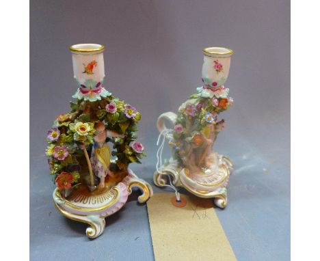 A pair of Meissen candlesticks with central figures surrounded with foliage. H.18cm 