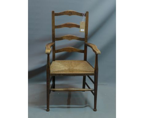 An early 20th century oak ladder back armchair with rush seat. 