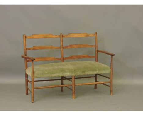 An Arts and Crafts oak two seater ladder back settee, shaped arms and double stretcher, 120cm wide
