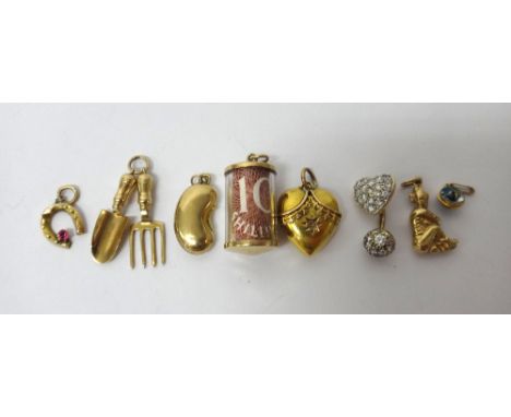 A Victorian gold heart shaped pendant, detailed indistinctly 15, six mostly 9ct gold charms, including; a garden trowel and f