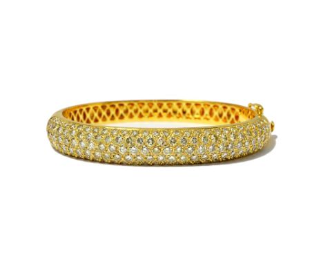 A gold and diamond set oval hinged bangle, the curved front mounted with five rows of circular cut diamonds, on a snap clasp,