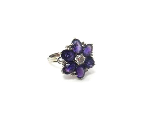 A diamond and amethyst set hexagonal cluster ring, claw set with the principal circular cut diamond at the centre, in a surro