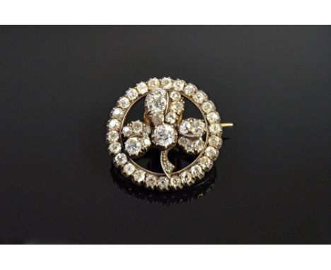 A gold backed and silver set diamond circular brooch, the centre with a trefoil shaped motif mounted with cushion shaped diam