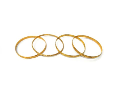 A gold circular bangle, with engraved decoration, detailed 18 K and three further gold bangles, with engraved decoration, det