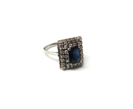 A white gold, sapphire and diamond set rectangular cluster ring, claw set with the cut cornered rectangular step cut sapphire