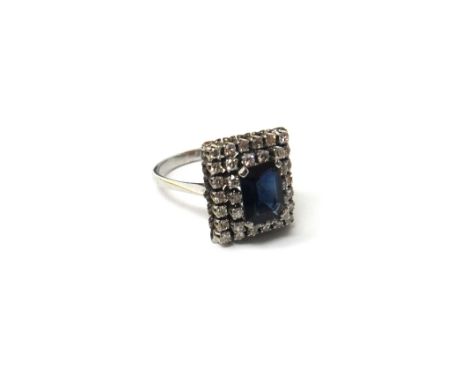 A white gold, sapphire and diamond set rectangular cluster ring, claw set with the cut cornered rectangular step cut sapphire