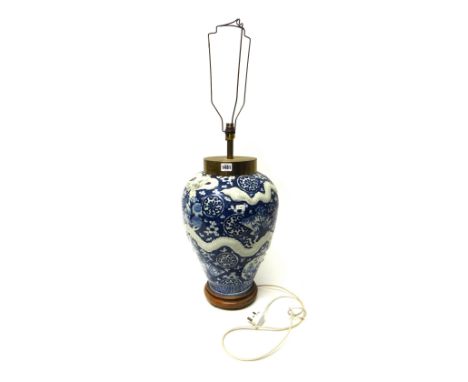 A blue and white ovoid vase, circa 1900, moulded with two white dragons against a prunus and `cracked-ice' ground, adapted as