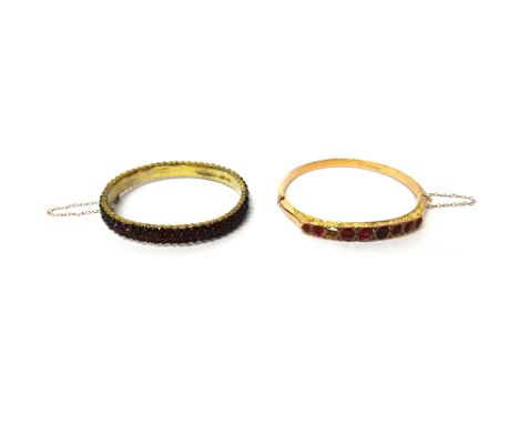 A Bohemian garnet set oval hinged bangle, the back and the front pave set with Bohemian garnets, on a snap clasp and a 9ct go