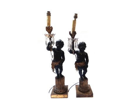 A pair of ebonised and giltwood figural table lamp lustres, 19th century, each carved as a putti atop a Corinthian column bas