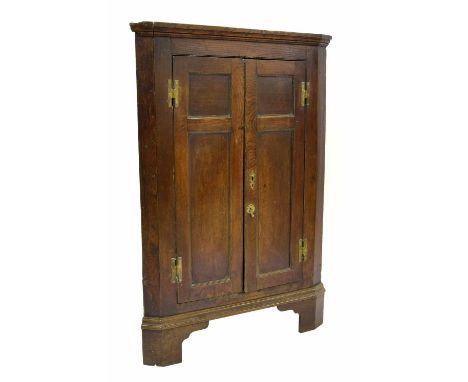 George III oak freestanding corner cupboard, with twin panelled doors opening to reveal a shelved interior, supported upon br