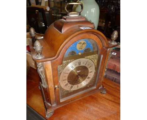 An Urgos arch topped bracket clock in a walnut-style case with ormulu mounts and finials, a silvered chapter ring and moon ph