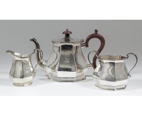 An Elizabeth II silver octagonal three piece tea service of panelled form, comprising - teapot with wood finial and scroll ha