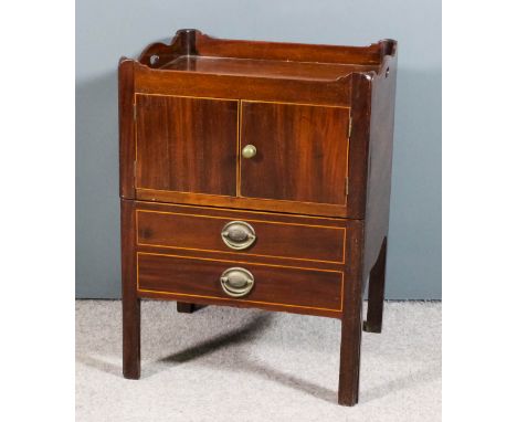 A George III mahogany rectangular tray top bedside cabinet, the shaped tray top with handle cut-outs, enclosed by two doors, 