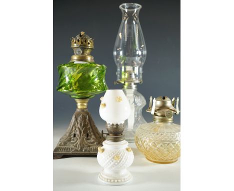 An oil lamp with amber glass reservoir together with three other lamps