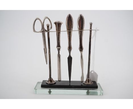 A 1930s silver manicure set stand by Sanders &amp; Mackenzie, having a terraced glass and composition platform base, together