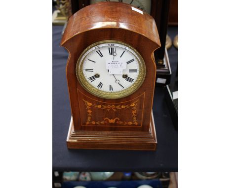 An Edwardian mahogany inlaid eight day mantle clock, the white enamelled dial with black Roman numerals and two winder holes.