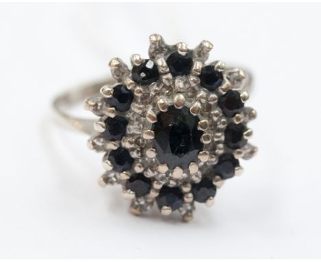 A sapphire and diamond cluster ring set in white metal (possibly 18ct gold) one claw and diamond missing.