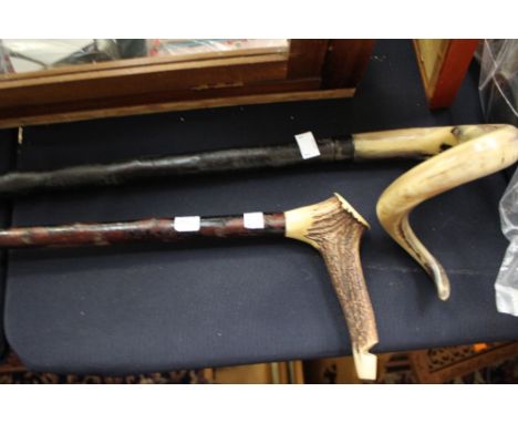 A curled horn handled walking stick, with another horn handled walking stick, the handle also being a whistle.