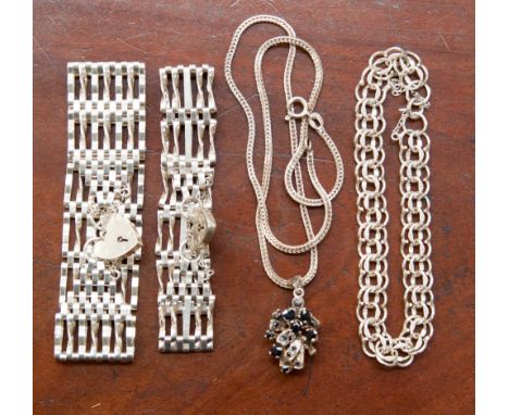 A white metal basket pendant set with sapphires, two white metal gate bracelets and a white metal link bracelet, stamped 'STE