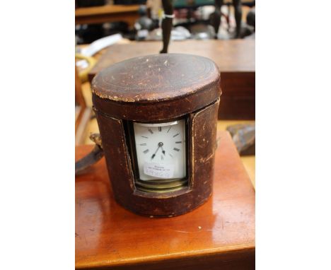 An oval carriage clock, with case and key, the glass to the clock bevelled, the metal surround is engraved.