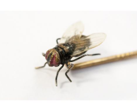 A fly stick pin, the realistic model of a fly mounted to the top of a yellow metal stick pin.